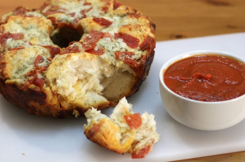 Pizza monkey bread on a cutting board with bowl of marinara sauce.