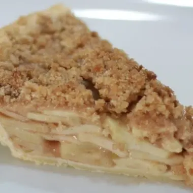 Slice of apple crumb pie on a white plate