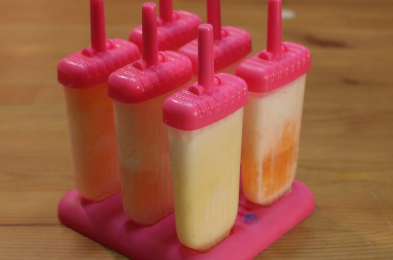 Homemade orange creamsicles on a wooden table