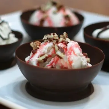 chocolate balloon bowls filled with ice cream on a white plate