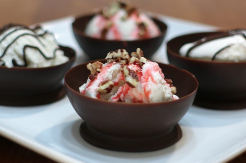 chocolate balloon bowls filled with ice cream on a white plate