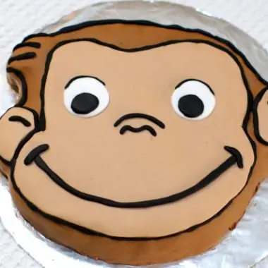 Curious George cake on a cake board covered in aluminum foil.