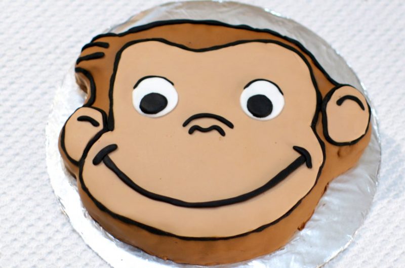 Curious George cake on a cake board covered in aluminum foil.