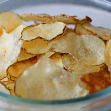 Pile of microwave potato chips in a clear bowl.