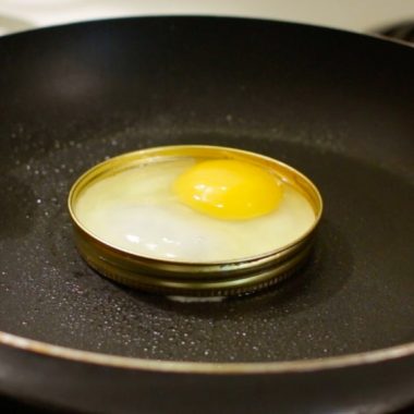 An egg in a mason jar ring in a skillet.