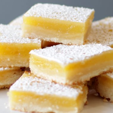 Homemade lemon bars stacked on a white plate