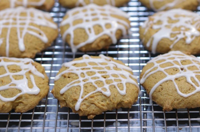 Several glazed pumpkin cookies on a wire cookie rack.