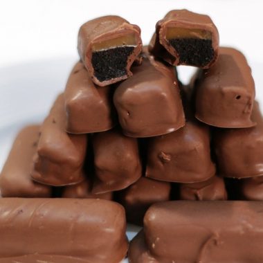 Oreo Twix Cookie bars stacked on a white plate.