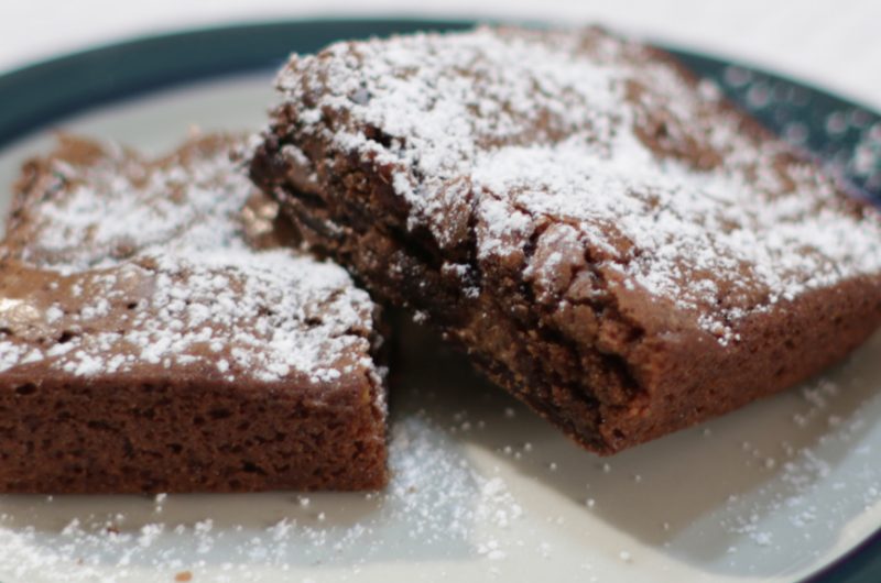 Two homemade brownies with powdered sugar on a plate.