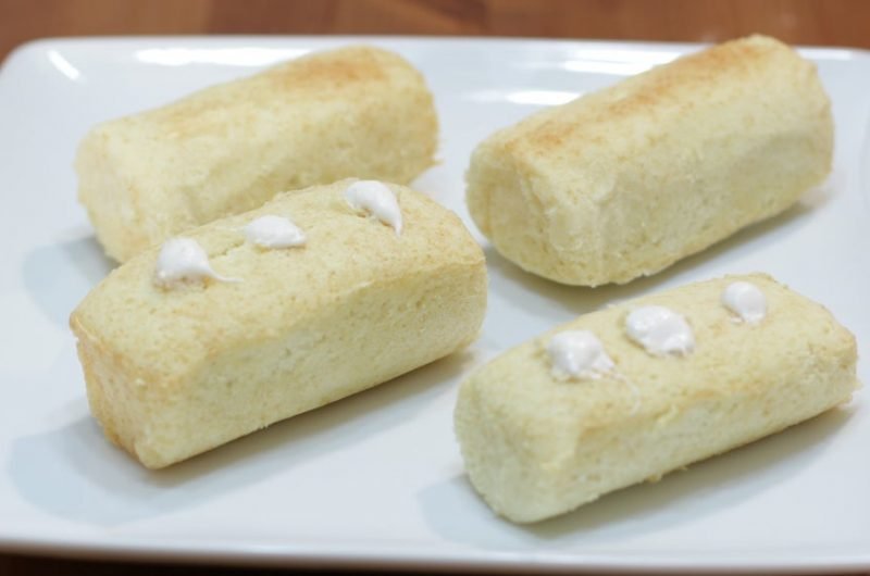 Four homemade Twinkies on a white plate on a table.