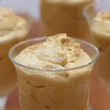 Pumpkin mousse in glasses on a wooden table.