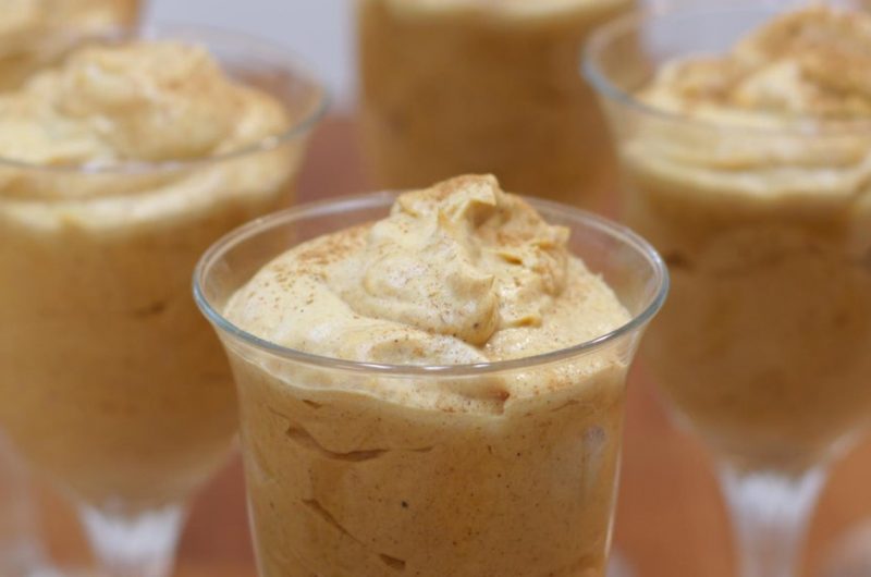 Pumpkin mousse in glasses on a wooden table.