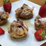 Four French toast bites on a white plate.