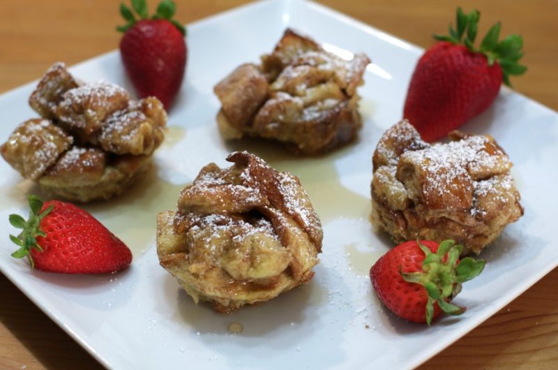 Four French toast bites on a white plate.