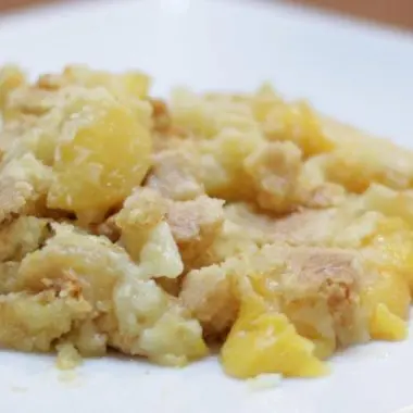White plate with a mound of cake mix peach cobbler on it.