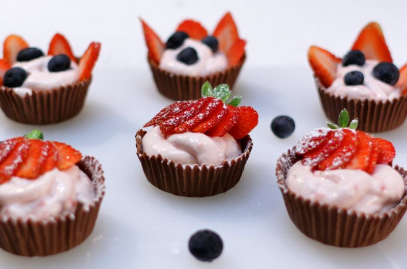 Strawberry cheesecake mousse chocolate cups on a white cutting board
