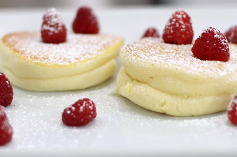 Japanese souffle pancakes on a white plate with raspberries