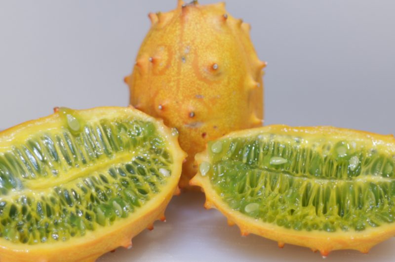 two halves of a kiwano melon on a cutting board