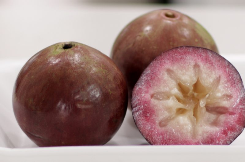 Three star apples on a white plate.