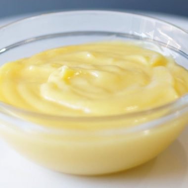 easy homemade lemon curd in a glass bowl on a white plate.