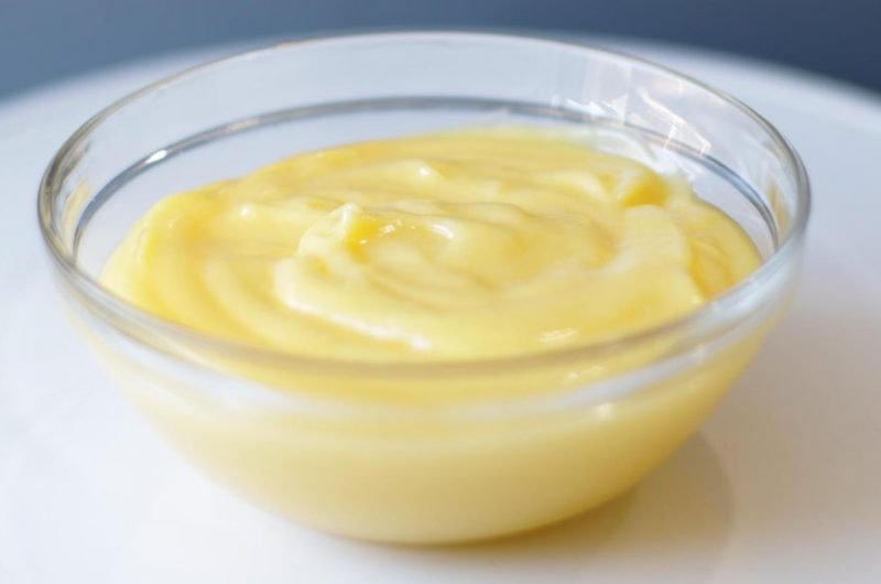 easy homemade lemon curd in a glass bowl on a white plate.
