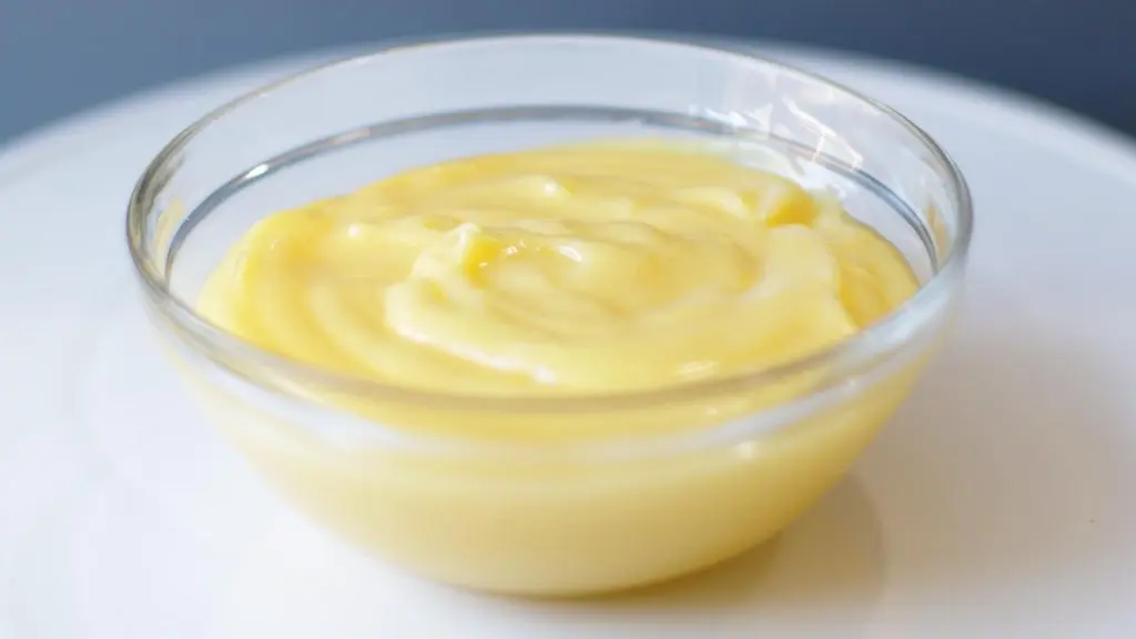easy homemade no bake lemon curd in a glass bowl on a white plate.