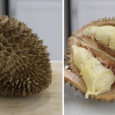 Sliced Durian Fruit next to a whole one on a counter.