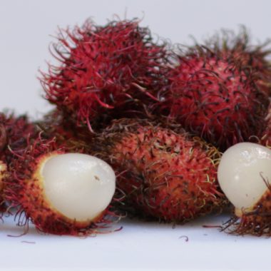 how to eat rambutan pile of rambutans on a white cutting board