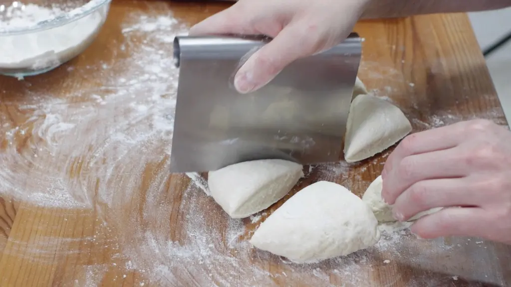 Hand cutting flatbread dough with a dough scraper.