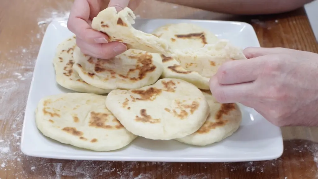 Hands tearing apart a flatbread