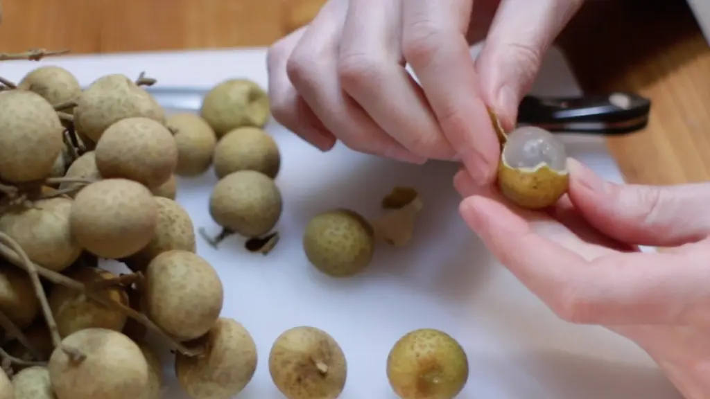 Hand peeling the longan fruit.