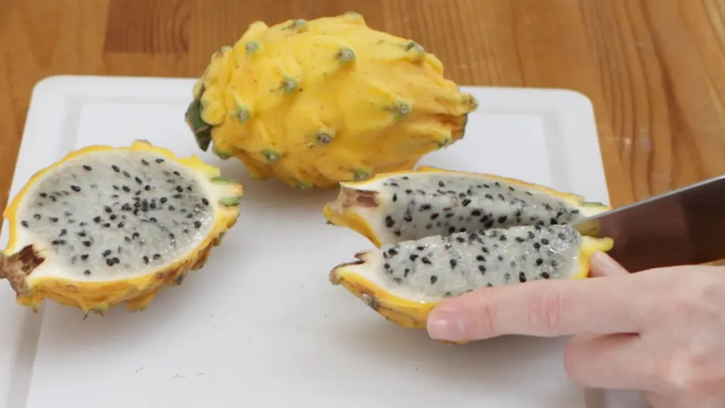 Knife quartering a yellow dragon fruit.
