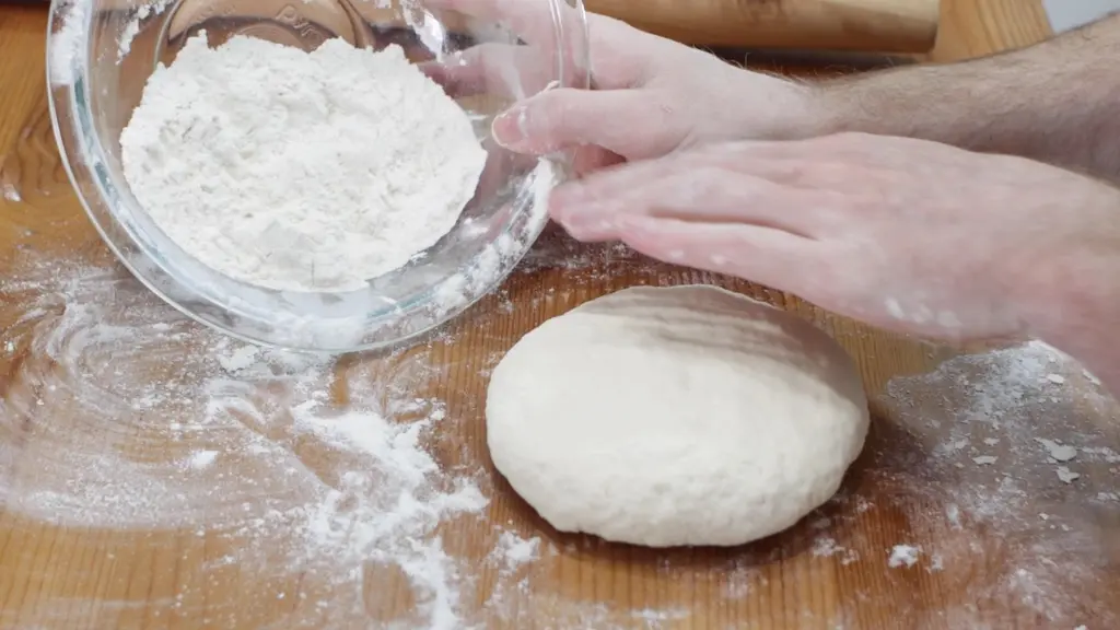 Flatbread dough shaped into a fat disc on a wooden table.