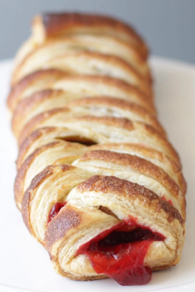 Braided strawberry puff pastry on a white plate.