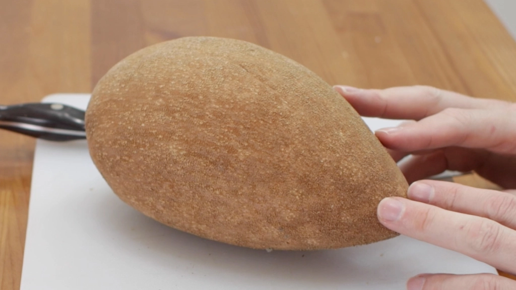Mamey sapote on a white cutting board.