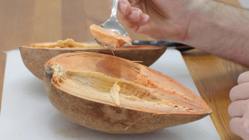 Hand scooping flesh from the mamey sapote.