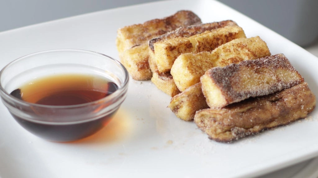 Plate of cinnamon french toast sticks with a bowl of maple syrup.