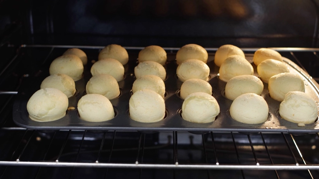Brazilian cheese bread in mini muffin pan baking in the oven.