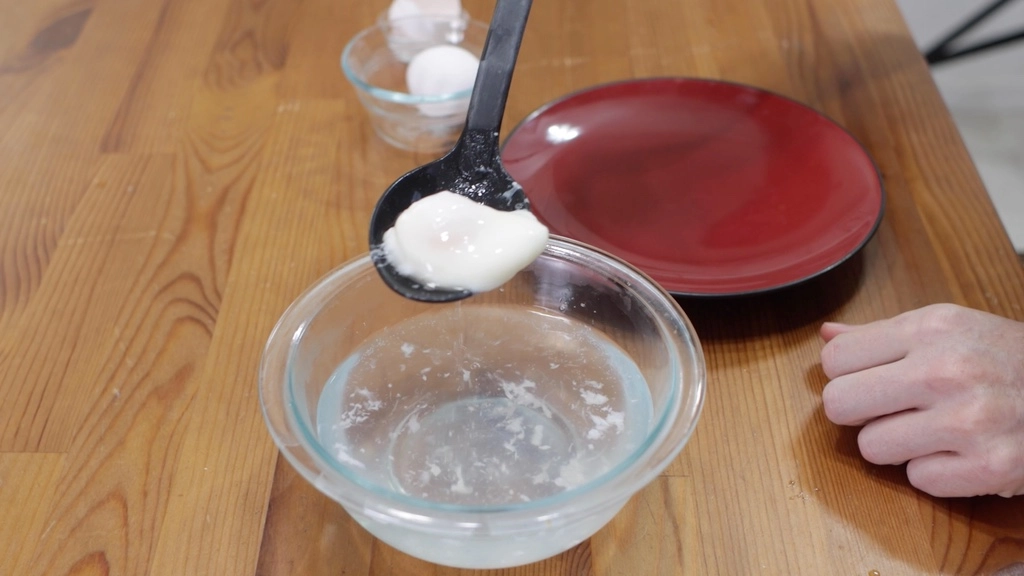 Perfect poached egg in a black slotted spoon.