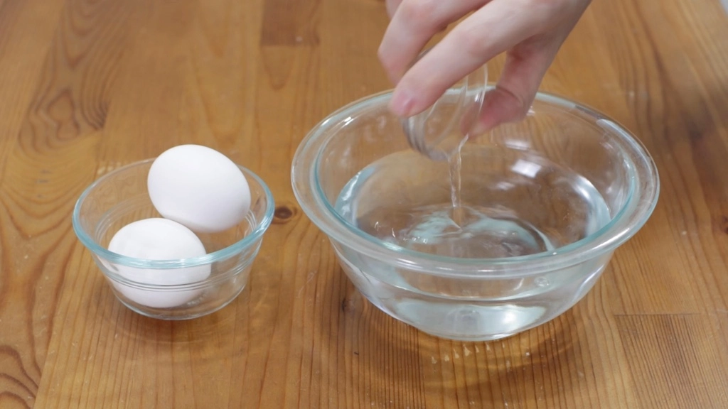 Vinegar being poured in water in a glass bowl.
