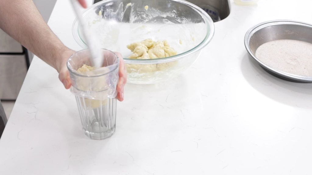 Hand filling a pastry bag with churro dough.
