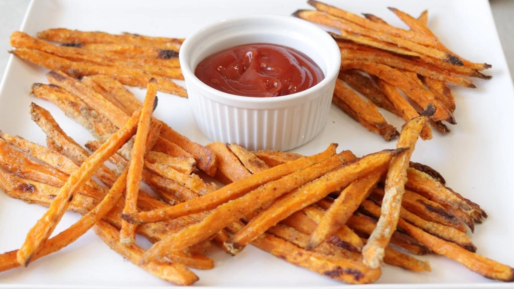 Piles of sweet potato fries with a bowl of ketchup