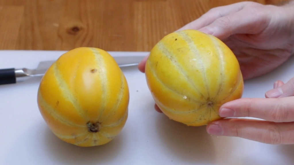 Two Korean melons sitting on a white cutting board.