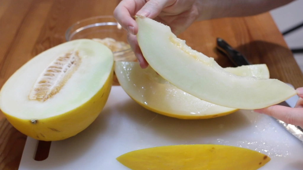 Sliced canary melon in fingers.