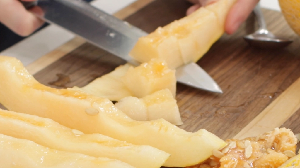 Knife slicing Hami melon creating chunks.