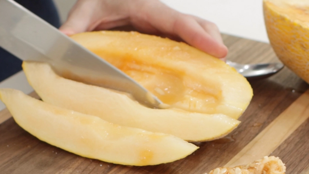 Slicing a hami melon on a brown cutting board.