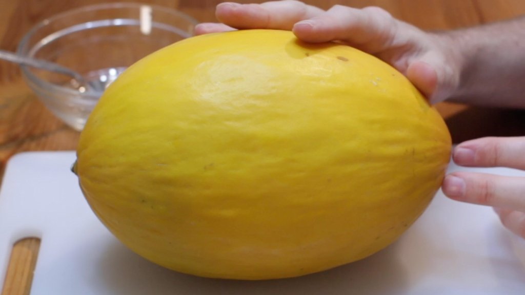 Hands holding a canary melon.