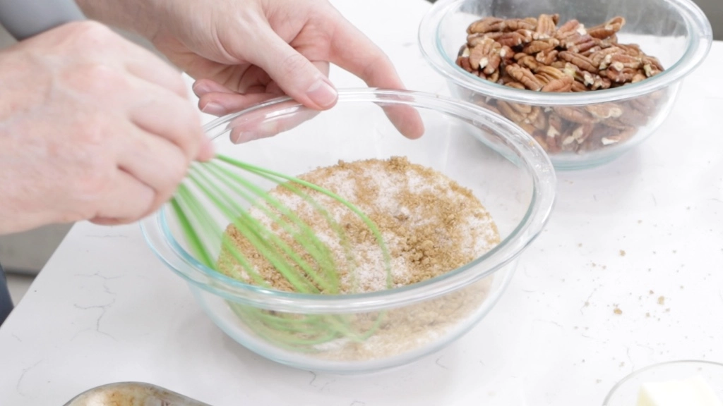 Hand whisking dry ingredients in a medium glass bowl.