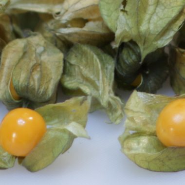 Goldenberries piled on a white cutting board.