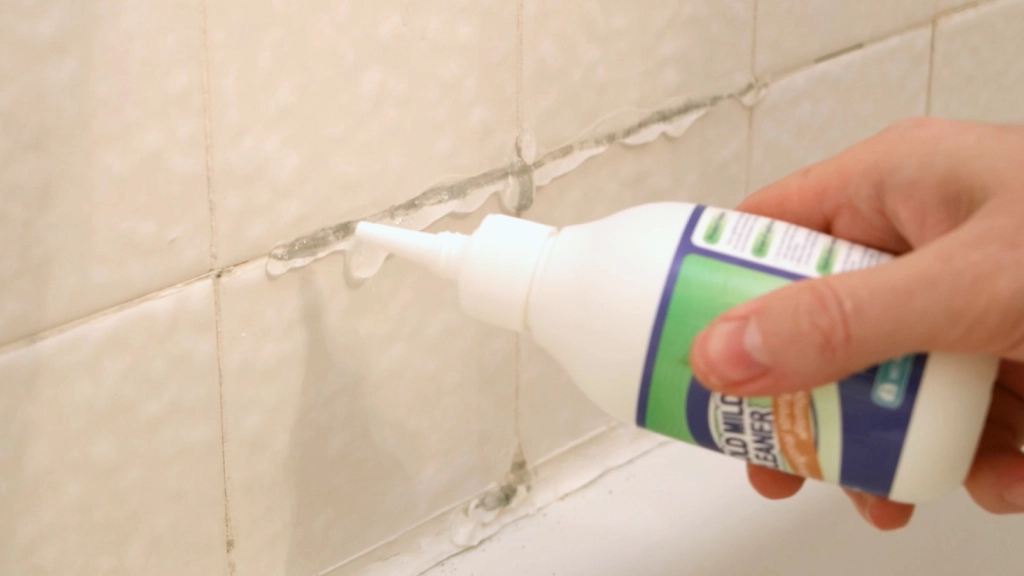 Hand applying mold mild cleaning gel to black mold shower tile.